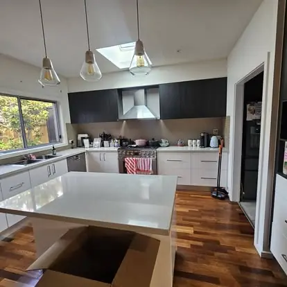 Finished kitchen with dark cabinetry, white benchtops and timber flooring
