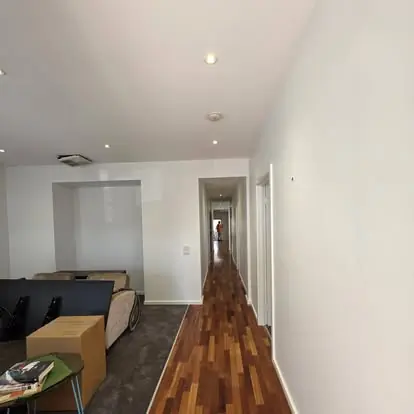 Freshly painted white hallway opening into a bright living area