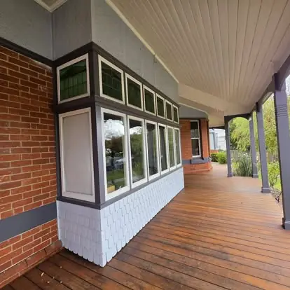 Timber verandah with painted trim along a brick home