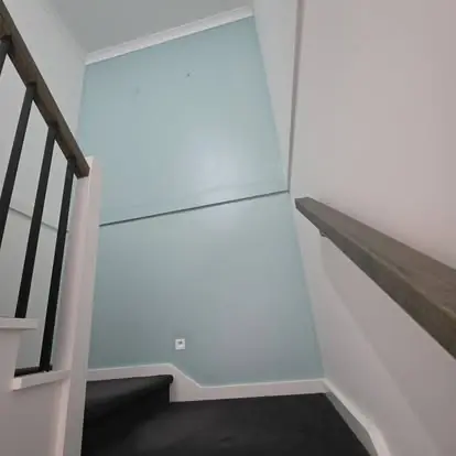 Stairwell feature wall painted pale blue beside a dark stair rail