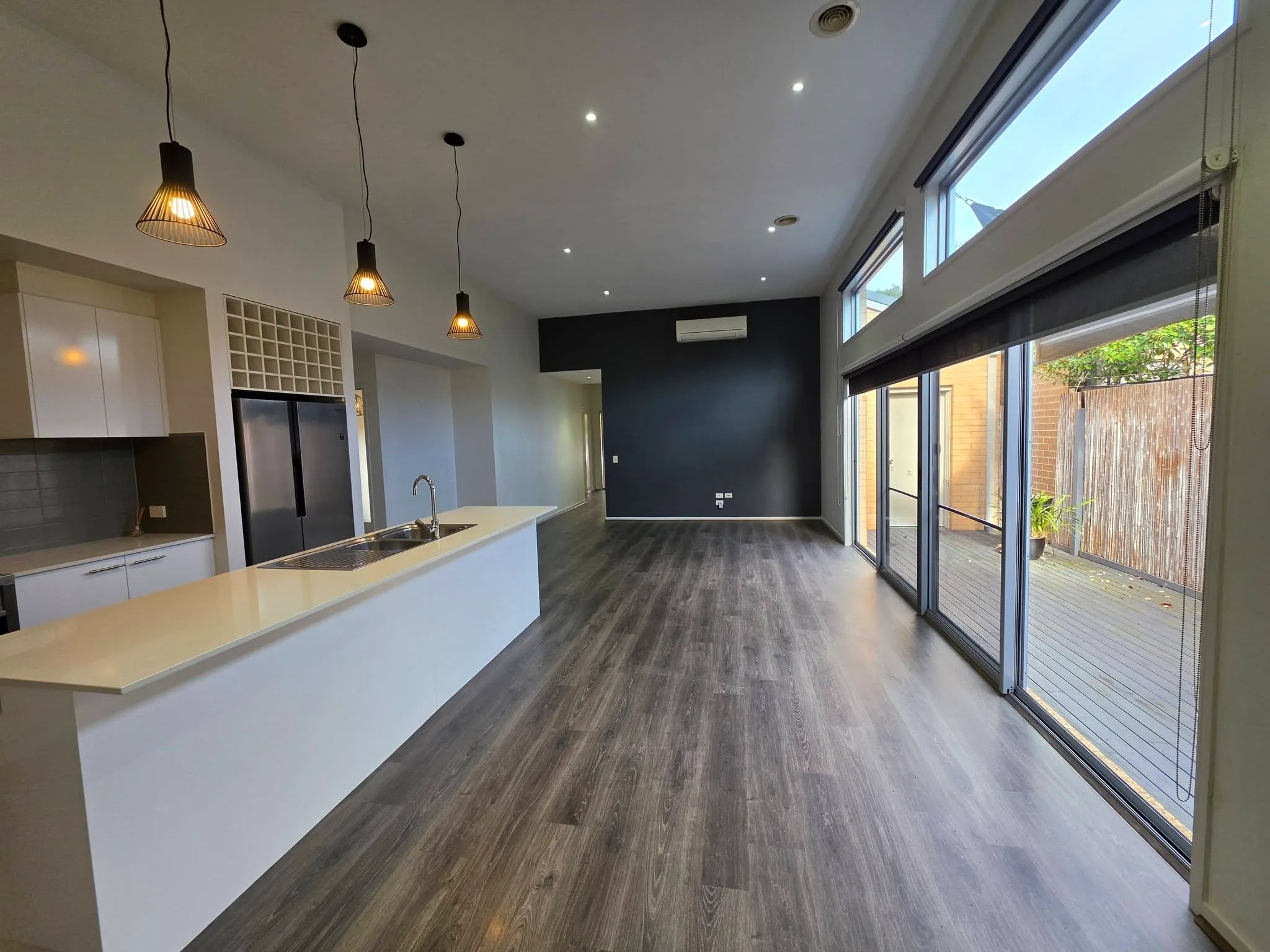 Modern open-plan kitchen and dining area with a dark feature wall and large sliding doors